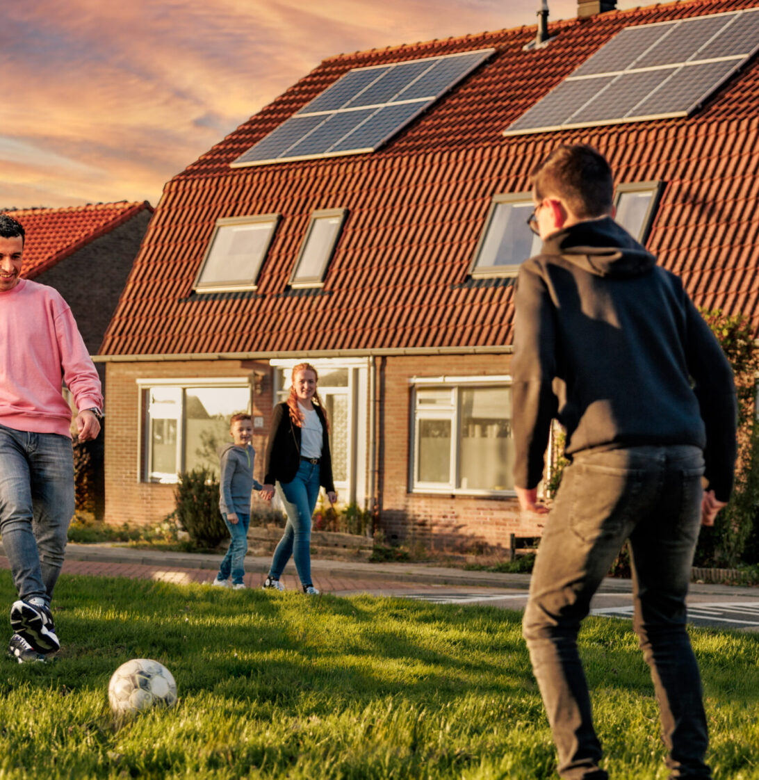 Voetballend gezin voor huis met zonnepanelen
