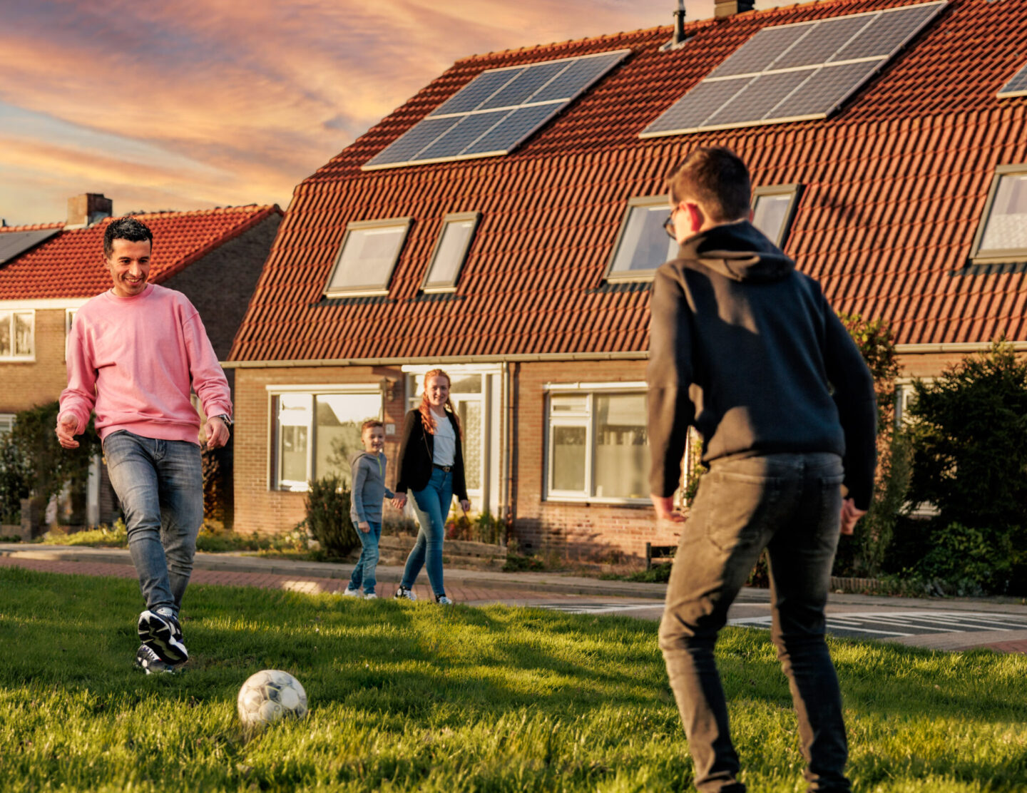 Voetballend gezin voor huis met zonnepanelen