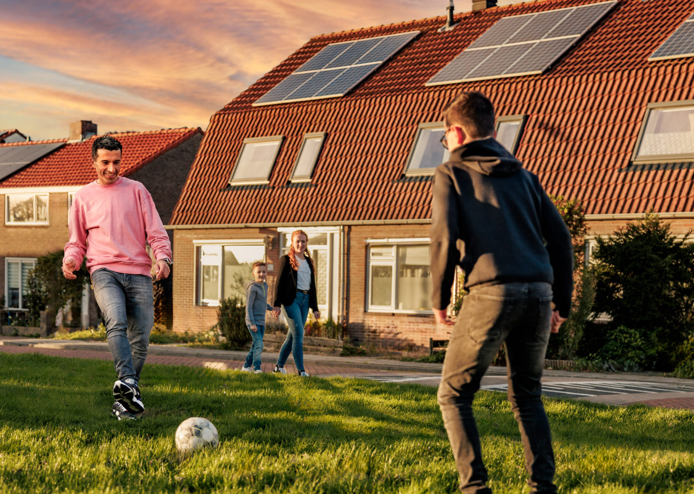 Voetballend gezin voor huis met zonnepanelen