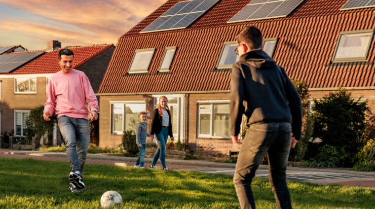 Voetballend gezin voor huis met zonnepanelen